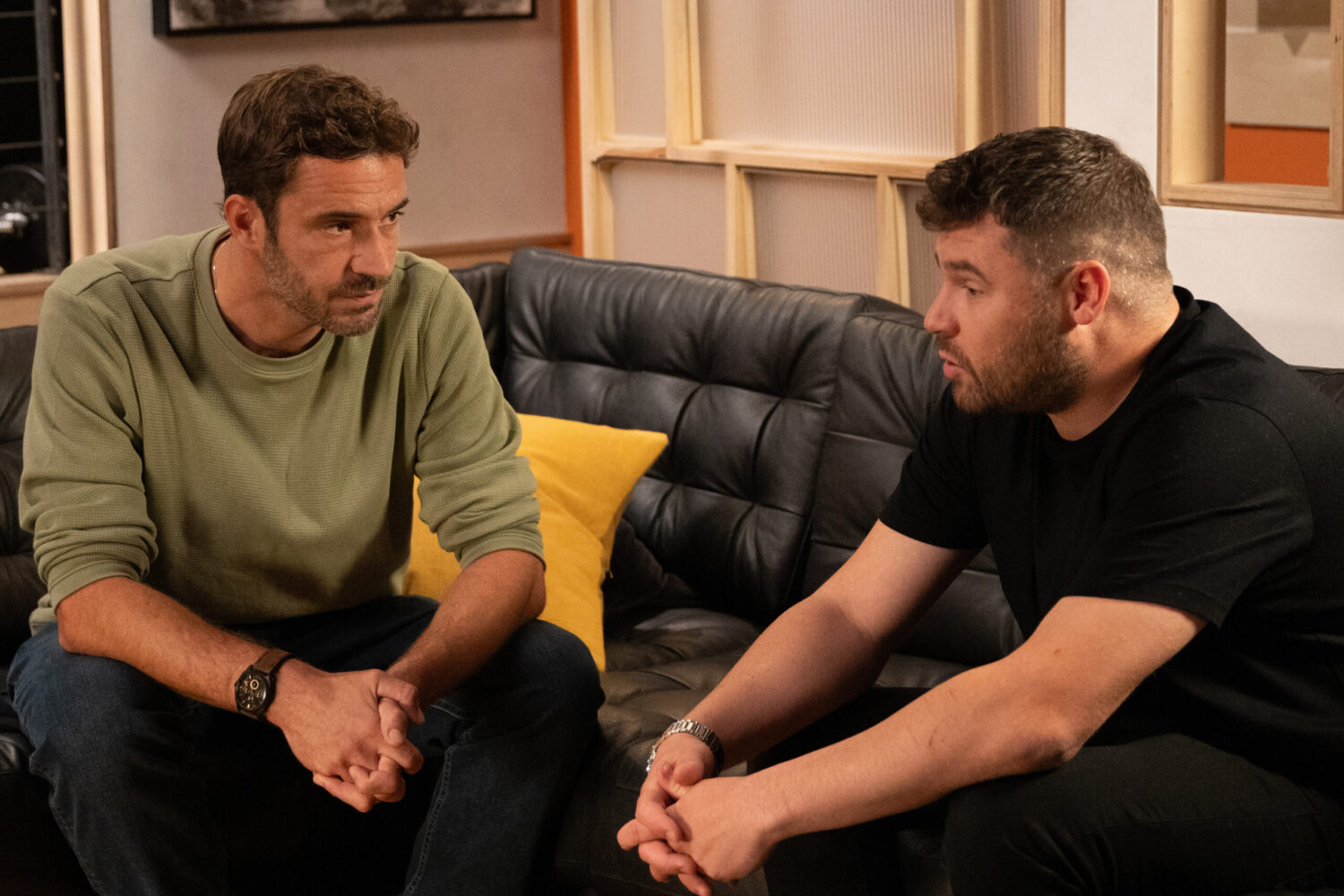 John and Aaron are talking on the sofa in Emmerdale