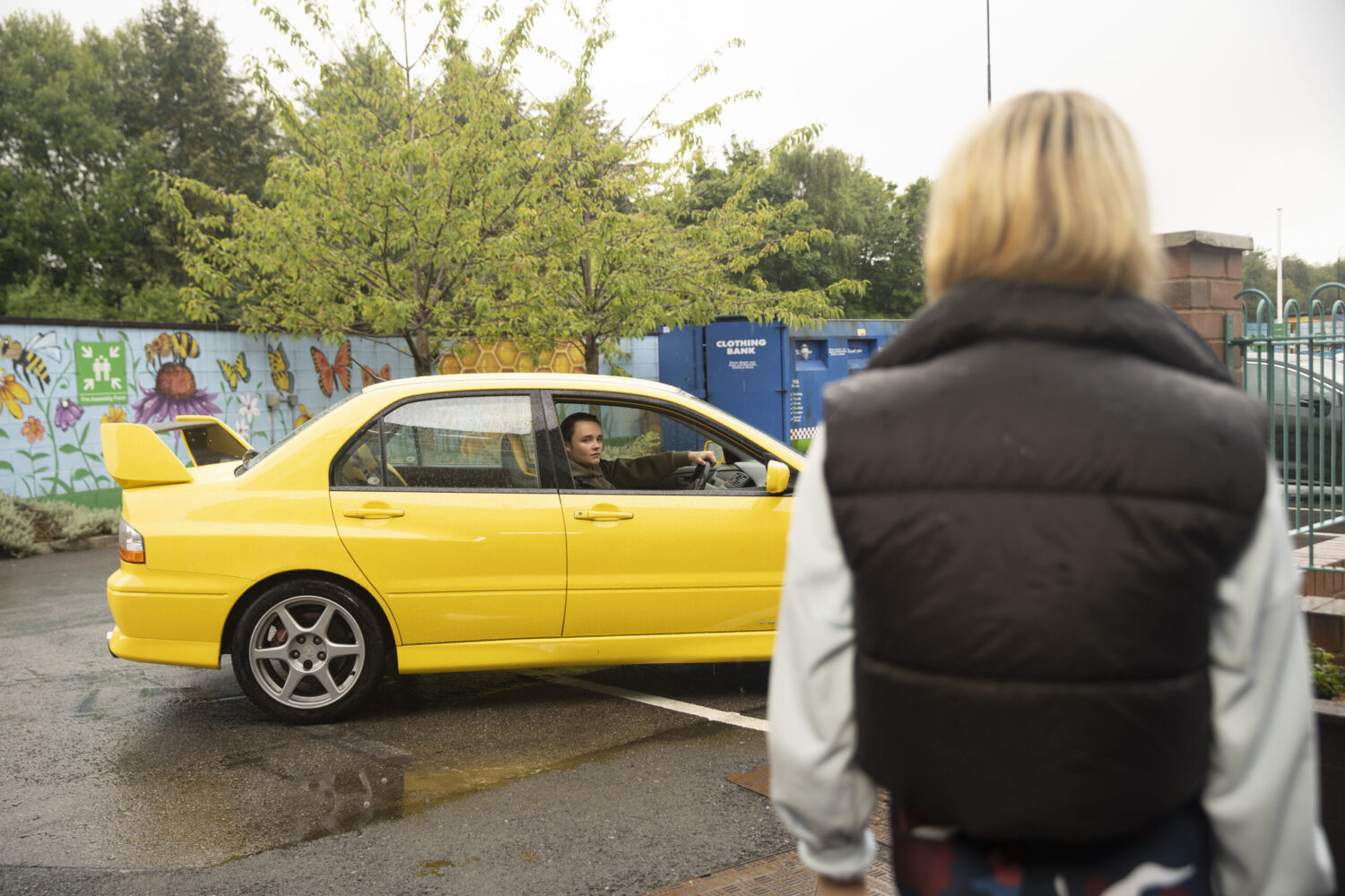 Logan in yellow car staring at Betsy