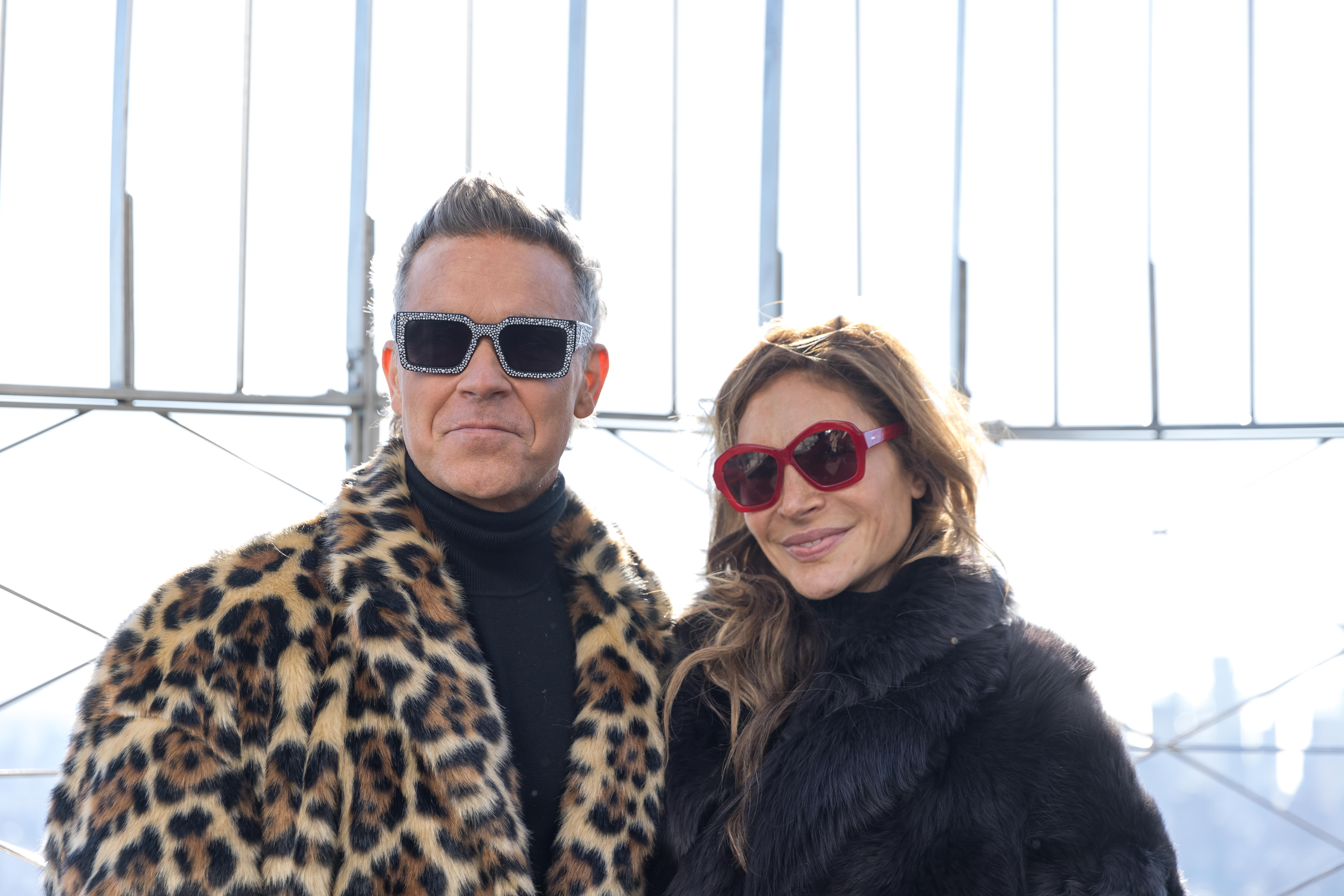 Robbie Williams and Ayda Field in coats smiling