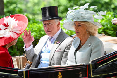 King Charles and Queen Camilla waving from a carriage